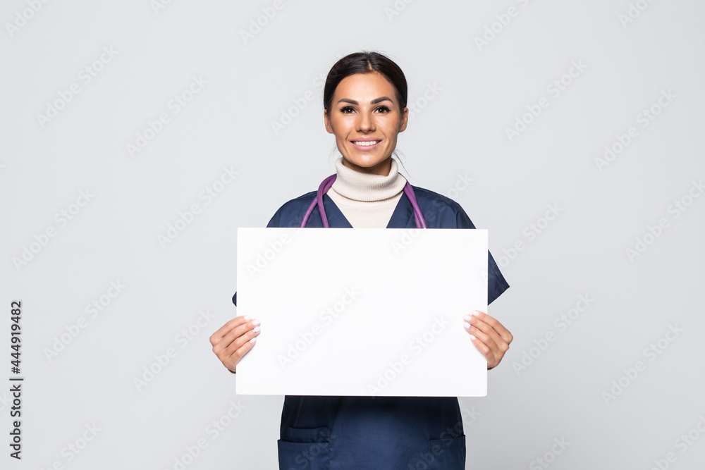 Young woman nurse or doctor in scrubs showing empty blank sign board with copy space isolated on white background. Young woman nurse or doctor in scrubs showing empty blank sign board with copy space isolated on white background.