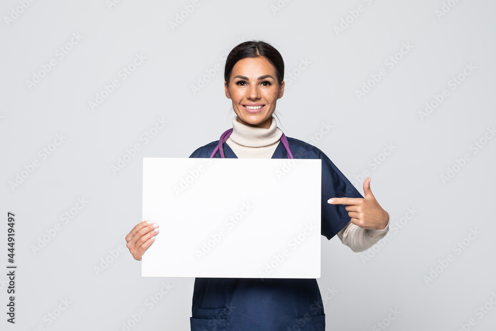 Young woman nurse or doctor in scrubs showing empty blank sign board with copy space isolated on white background. Young woman nurse or doctor in scrubs showing empty blank sign board with copy space isolated on white background.