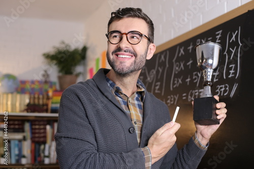 Math teacher holding a trophy in classroom