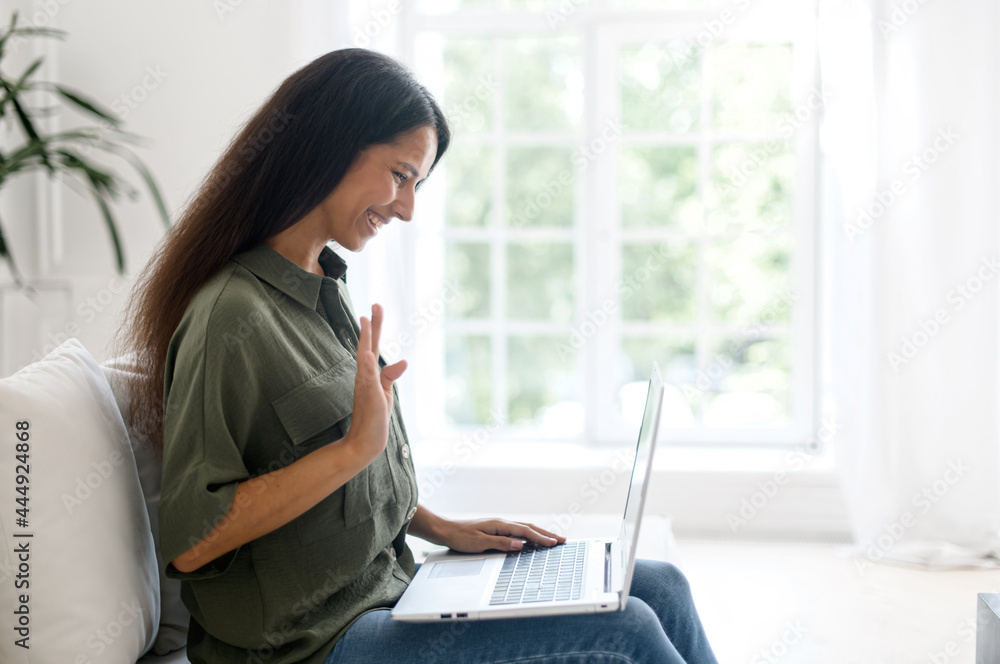 Positive smart young indian female freelancer or a student sitting on the couch with laptop on the lap, happy young eastern woman taking a part in virtual meeting, video calling and talking online, Positive smart young indian female freelancer or a student sitting on the couch with laptop on the lap, happy young eastern woman taking a part in virtual meeting, video calling and talking online,