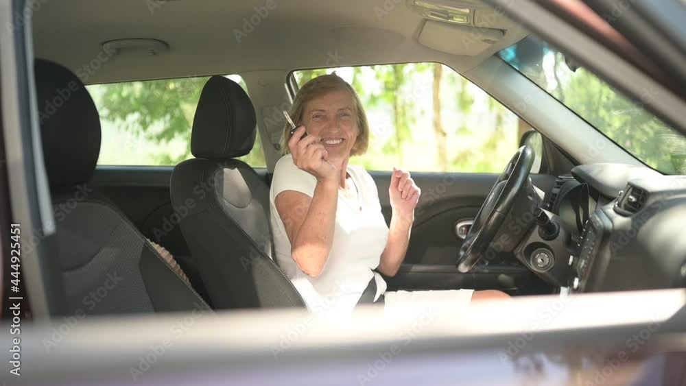Happy senior woman driving sitting in new car, dancing with key smiling looking at camera enjoying journey.Driving courses and life insurance concept. Retired people activity concept Happy senior woman driving sitting in new car, dancing with key smiling looking at camera enjoying journey.Driving courses and life insurance concept. Retired people activity concept