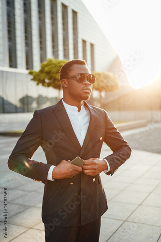 Stylish black businessman tying his jacket agianst cityscape photo