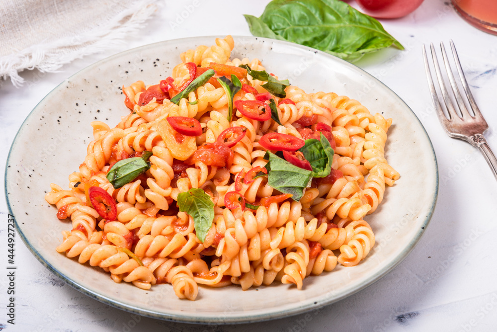 Marinara pasta in a plate close-up, high key - vegetarian girandole pasta with tomato sauce and fresh basil in a plate, close-up Marinara pasta in a plate close-up, high key - vegetarian girandole pasta with tomato sauce and fresh basil in a plate, close-up