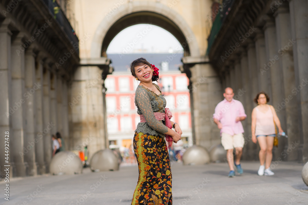 young happy and beautiful Asian woman wearing traditional Balinese kebaya dress - Indonesian girl in Bali clothes walking on street during holidays travel in Europe