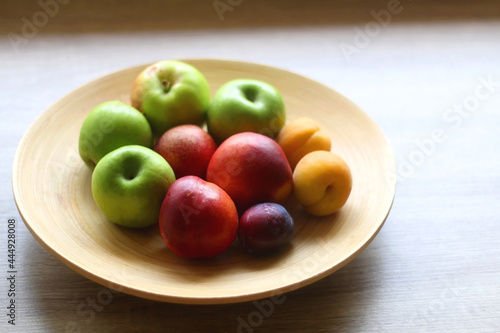 Wooden bowl with various colorful fruit on dark background. Selective focus.