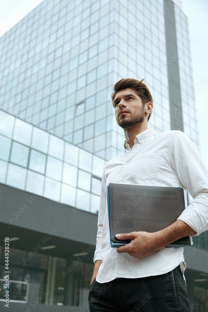Business man hold documents near modern skyscraper Business man hold documents near modern skyscraper