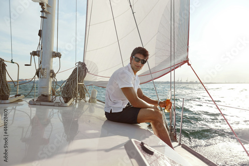 Young man drinking beer on his yacht in sea photo