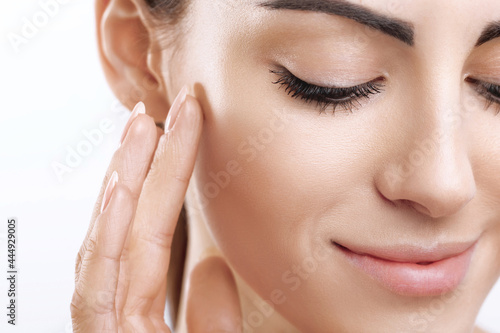 Closeup happy young woman applying cream to her face Skincare and cosmetics concept. Cosmetics. Woman face skin care.Natural makeup, touching face.