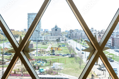 Large green park with lawns and tracks on modern city street on sunny day view through window with golden decorative elements