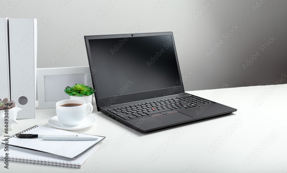 Office pc desk workspace in Home interior. Long web banner. White table with laptop for remote work or study. Black laptop with blank display layout template on white background. Office pc desk workspace in Home interior. Long web banner. White table with laptop for remote work or study. Black laptop with blank display layout template on white background.