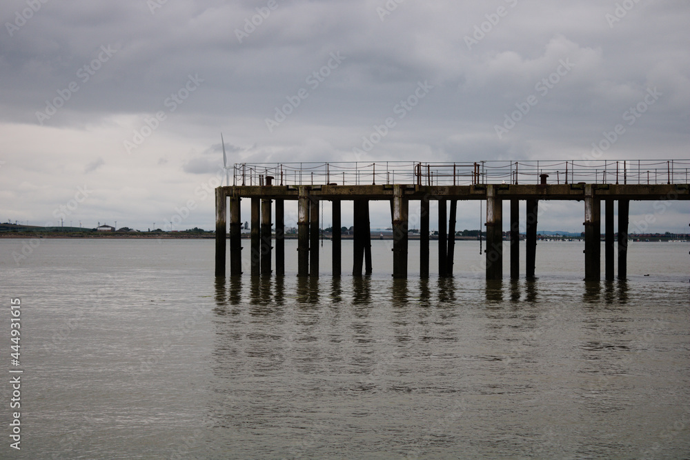 Part of old abandoned pier in the sea, Kent, England, Isle of Grain, on a cloudy day