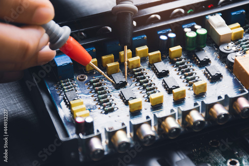 Technician checking ic on circuit board with multimeter