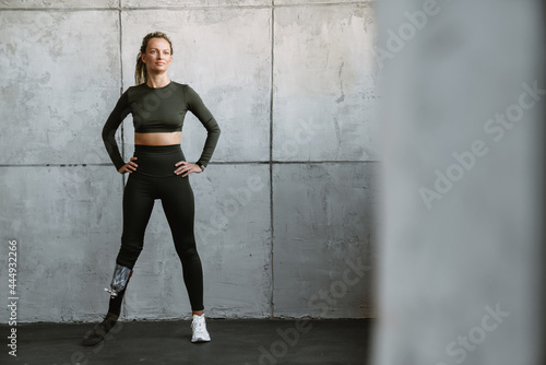 Young sportswoman with prosthesis standing while working out indoors