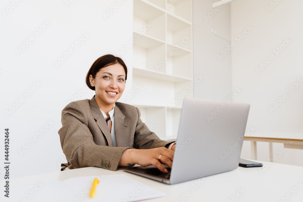 Young woman working with laptop while sitting at desk in office Young woman working with laptop while sitting at desk in office