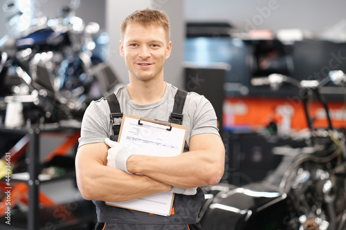 Handsome auto mechanic posing in car service and holding documents in hands © H_Ko