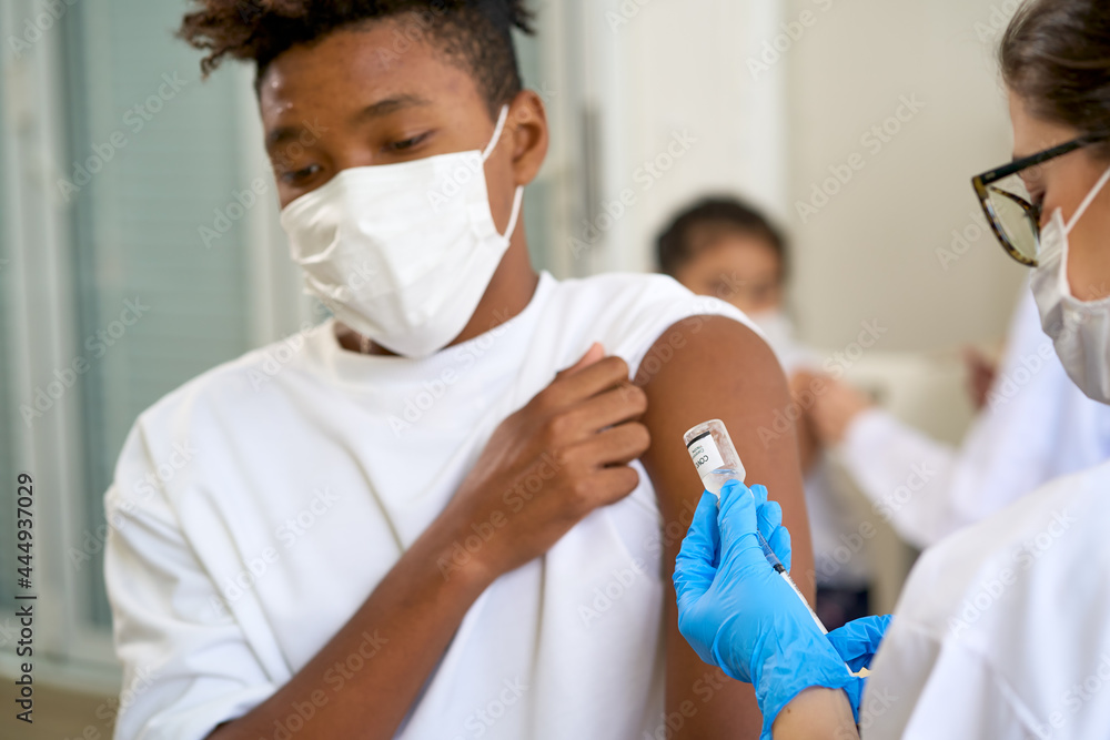 Vaccination process with doctor to inject to african-american patient in hospital , covid19 pandemic situation