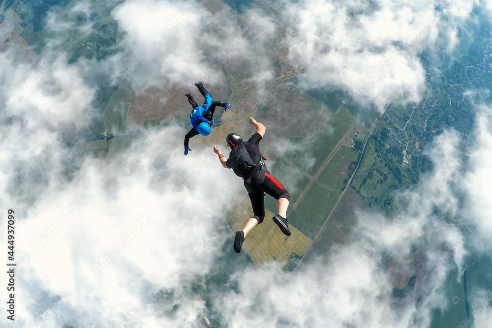 Two skydivers over the clouds during freefall - obrazy, fototapety, plakaty 