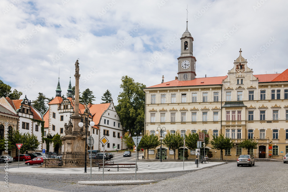 Benesov nad Ploucnici, North Bohemia, Czech Republic, 26 June 2021: Marian Column with baroque statues at main town square, old saxoxy renaissance Morzinov Castle and Town Hall at summer sunny day