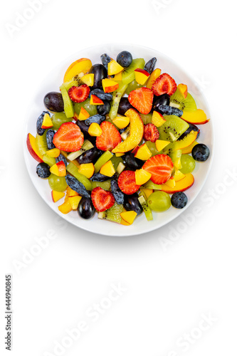 Fruit salad in a white plate  bowlmade of fresh fruits from grapes  nectarine  kiwi and strawberries  blueberries  honeysuckle  isolated on a white background.Top view  copy of the space