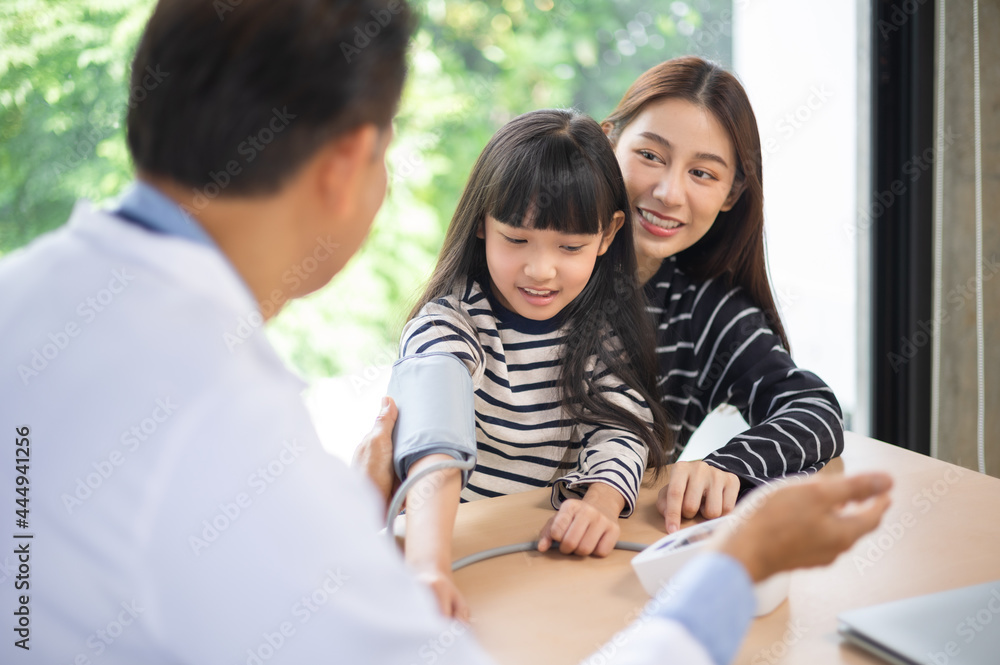 Asian doctor examining a girl body by stethoscope at hospital .Hospital and Insurance Concept. Measuring blood pressure and checking pulse Asian doctor examining a girl body by stethoscope at hospital .Hospital and Insurance Concept. Measuring blood pressure and checking pulse