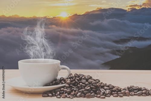 Coffee on wooden table with foggy landscape at morning.