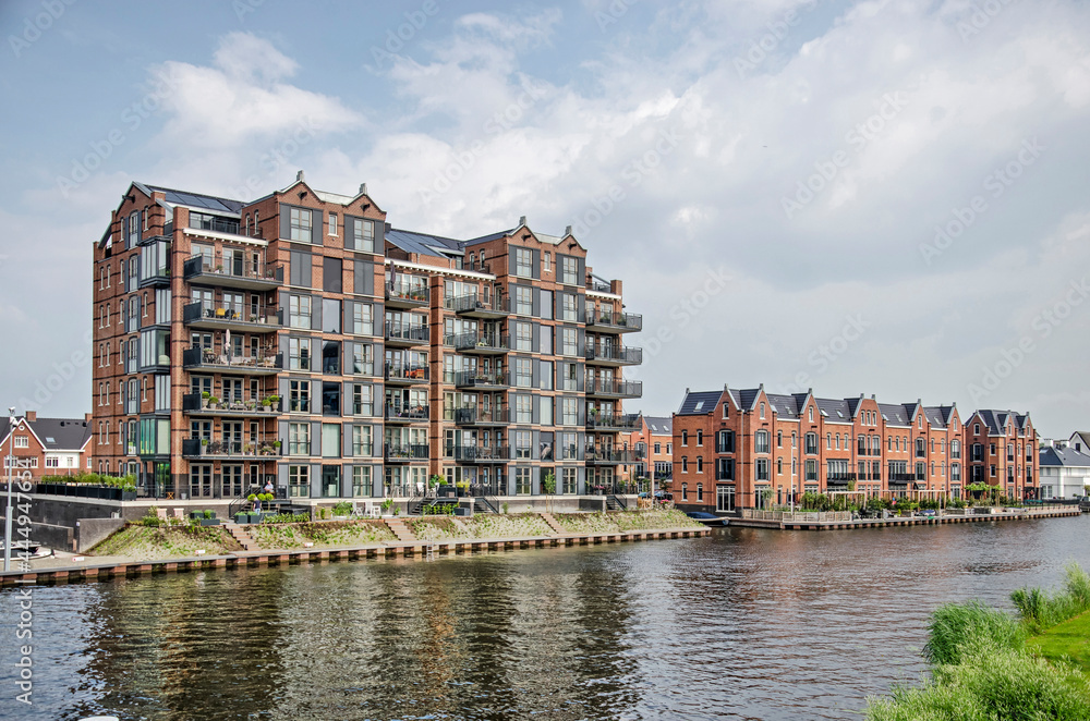 Oegstgeest, The Netherlands, July 11, 2021: recently built residential buildings on the banks of the river Oude Rijn, imitating the looks of converted old warehouses