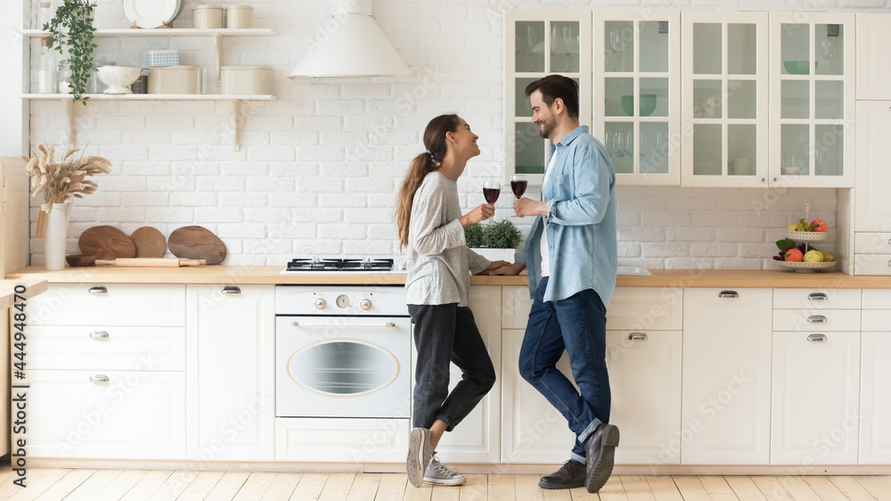 Couple in love chatting standing in cozy kitchen celebrate life event drinking red wine. Romantic date, relationships, new house homeowners family, repairs services, kitchen furniture services concept Couple in love chatting standing in cozy kitchen celebrate life event drinking red wine. Romantic date, relationships, new house homeowners family, repairs services, kitchen furniture services concept