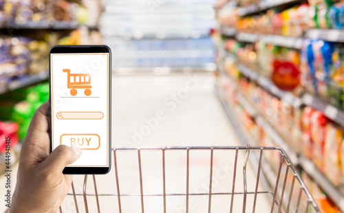 Man using phone in hand to shop online against supermarket background. online market concept.