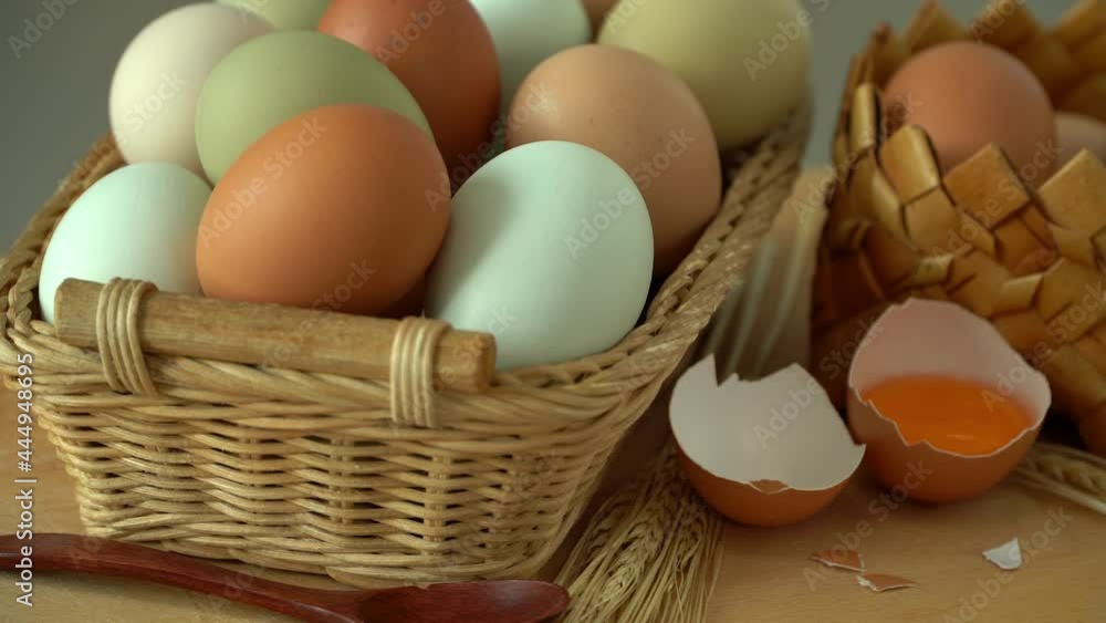 Wicker basket with fresh raw eggs rotate in wooden cutting board. Natural, healthy farm food. Rustic products. Wicker basket with fresh raw eggs rotate in wooden cutting board. Natural, healthy farm food. Rustic products.