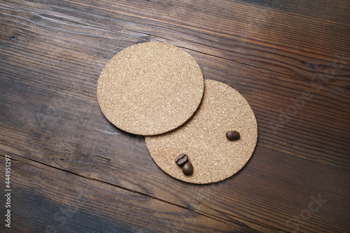 Blank cork beer coasters and coffee beans on wooden background. Responsive design template.