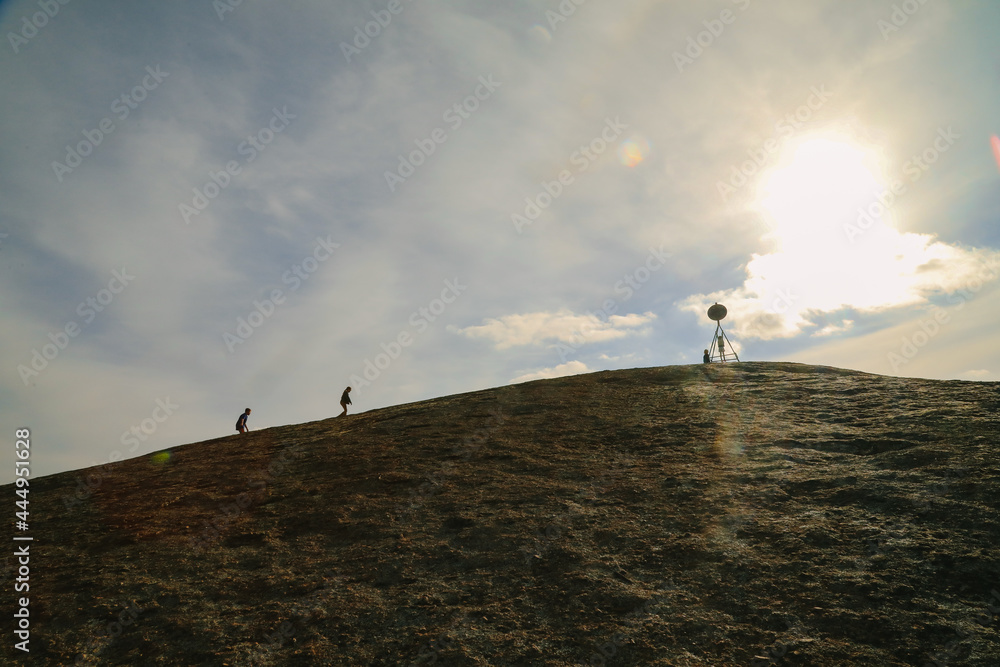 Silhouette image of people climbing to the summit of Mitiamo Rock in the Terrick National Park, Victoria, Australia