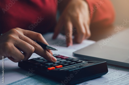 Close up businesswoman using calculator for doing math finance on wooden desk in the office. account, taxes, home budget concept