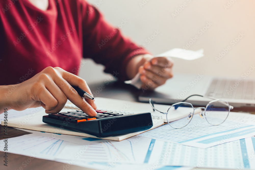Close up woman hand using a calculator and the other hand holds the bill with calculate about finance accounting. finance accounting concept Close up woman hand using a calculator and the other hand holds the bill with calculate about finance accounting. finance accounting concept