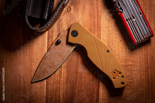 folding knife on a wooden surface with accessories  photo
