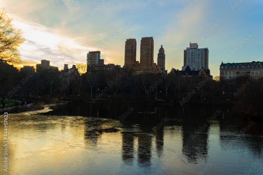 Sunset in Central Park with mirrored lake and backlit buildings