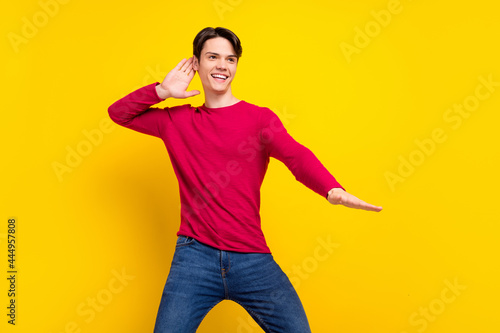 Photo of sweet charming young gentleman wear red pullover dancing looking empty space smiling isolated yellow color background © deagreez