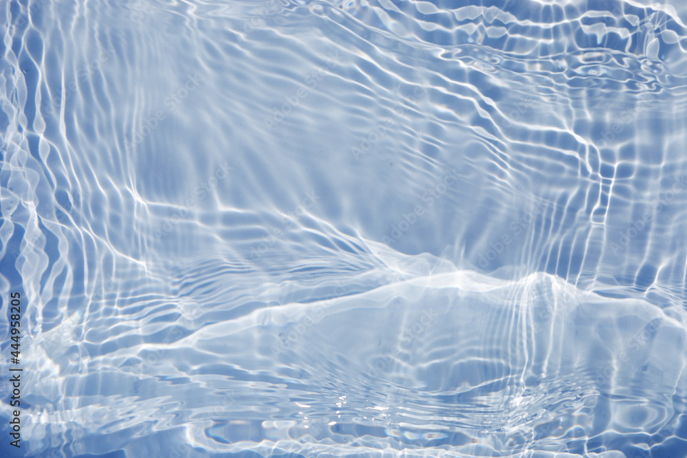 Blue clear water surface texture with splashes and bubbles. Trendy abstract water background. Water waves in sunlight.