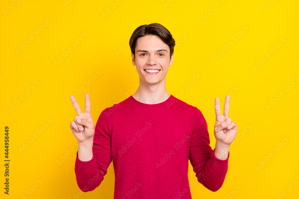 Photo of sweet pretty young gentleman wear red sweater showing two v-signs smiling isolated yellow color background Photo of sweet pretty young gentleman wear red sweater showing two v-signs smiling isolated yellow color background