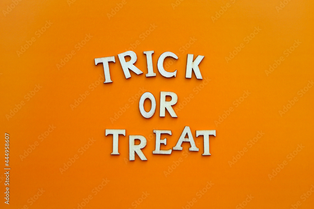 Obraz premium Words trick or treat. Wooden letters with lettering on top of orange background. Happy halloween