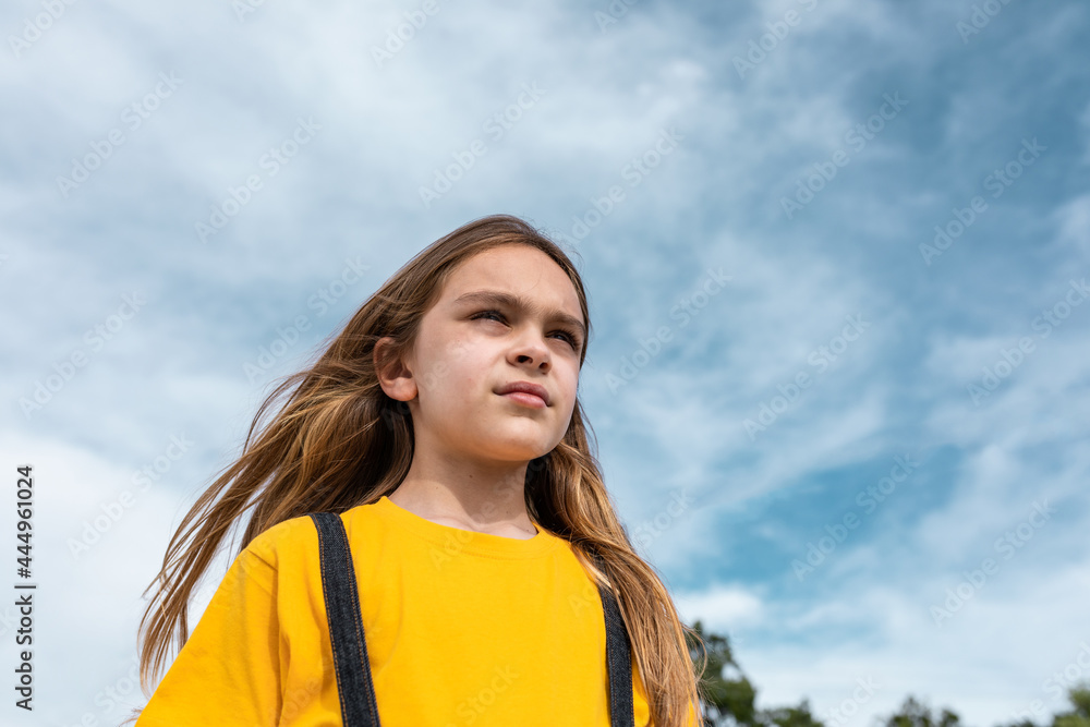 Serious teenager against cloudy sky in city Serious teenager against cloudy sky in city