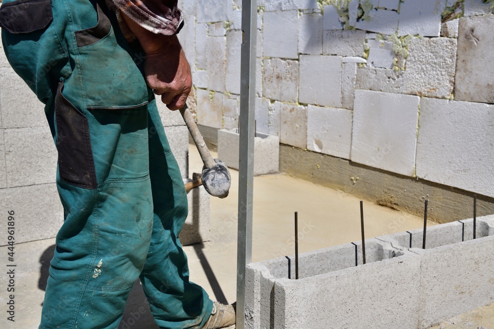 The mason on the construction site measures the perpendicularity of the walls with a spirit level