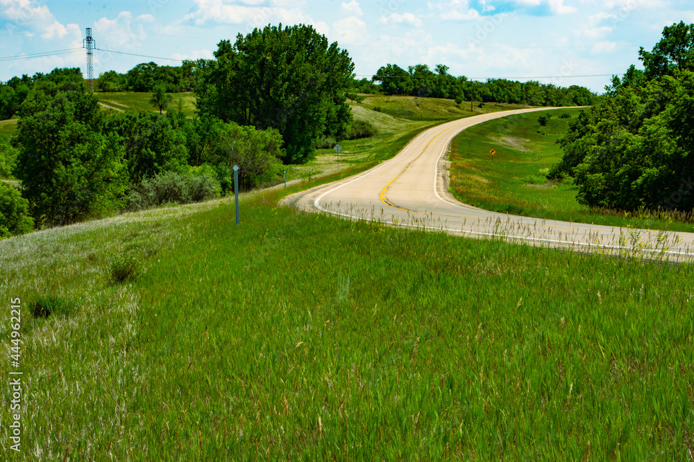 Paved two lane road leading away from congestion and into the peaceful countryside of rural America such as this scene in North Dakota.