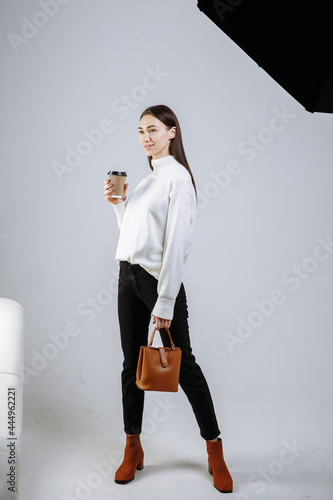 girl with bag and coffee posing on a light background