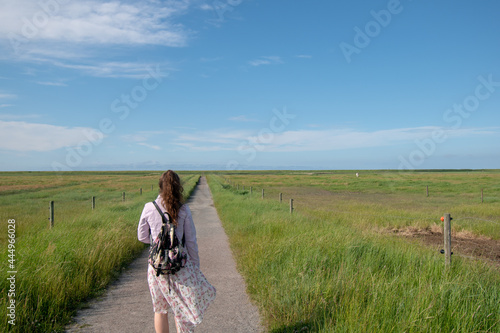 Girl walking through the path in the field during daytime