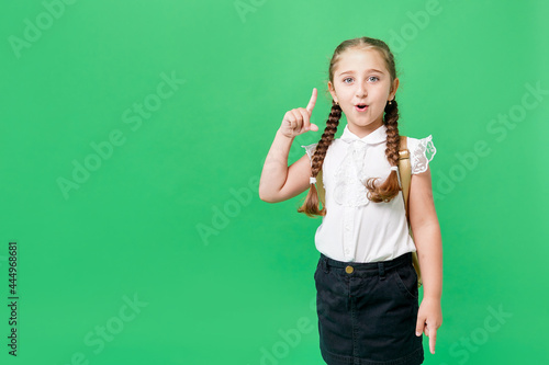 Cute little school girl with school bag on green background, copy space
