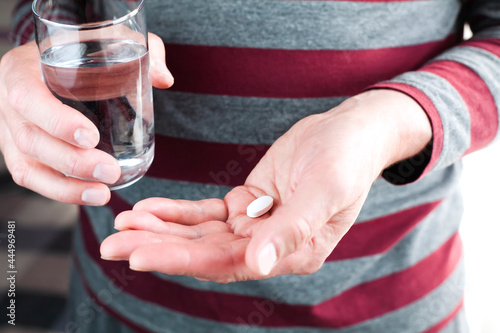 Senior man holds one pill and glass of water in hands. Taking medications with a doctor s prescription. Close-up.