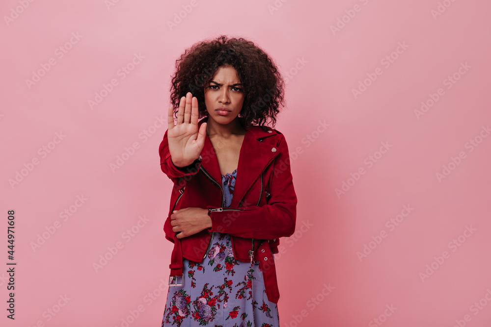 Charming girl in red jacket laughs on pink background. Happy curly woman in floral dress s,iling and looking into camera on isolated Charming girl in red jacket laughs on pink background. Happy curly woman in floral dress s,iling and looking into camera on isolated