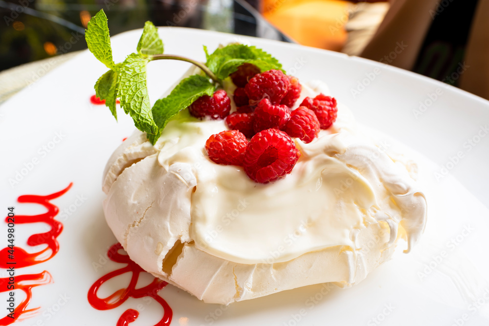 Sweet dessert with berries on a white plate. Meringue with raspberries and syrup. Sweet dessert with berries on a white plate. Meringue with raspberries and syrup.