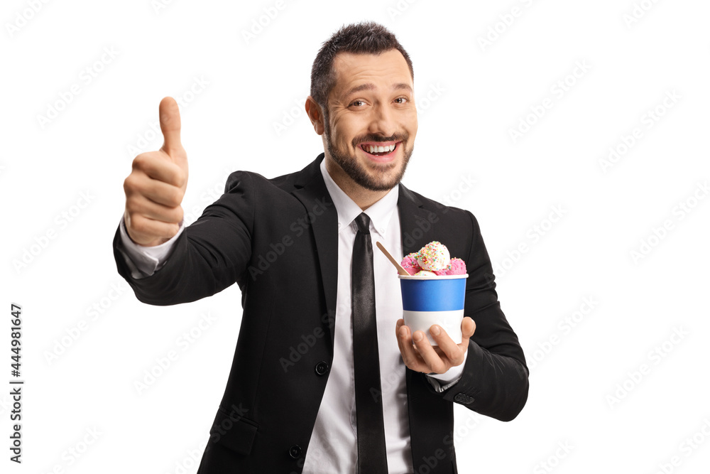 Happy young businessman eating ice cream in a paper cup and gesturing thumbs up Happy young businessman eating ice cream in a paper cup and gesturing thumbs up
