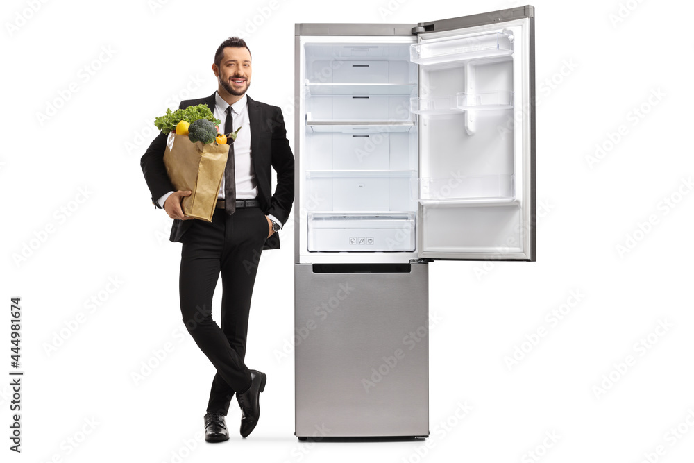 Full length portrait of a businessman with a grocery bag leaning on an empty open fridge Full length portrait of a businessman with a grocery bag leaning on an empty open fridge
